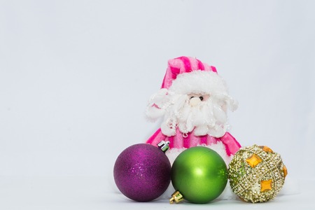 Adorable pink Santa Claus with three christmas spheres and white background.の写真素材