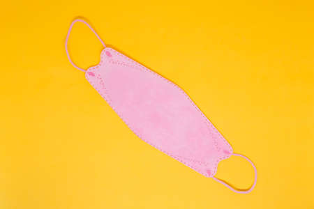 A Pink Mask in The Yellow Background with Flatlay Shotの写真素材