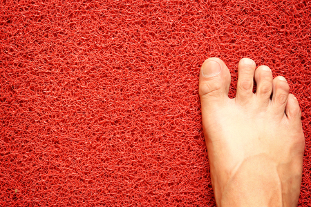 Foot on red doormatの写真素材
