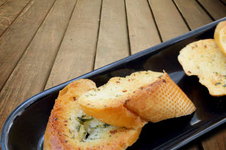 Close-up of a dish of garlic bread on wooden deck table