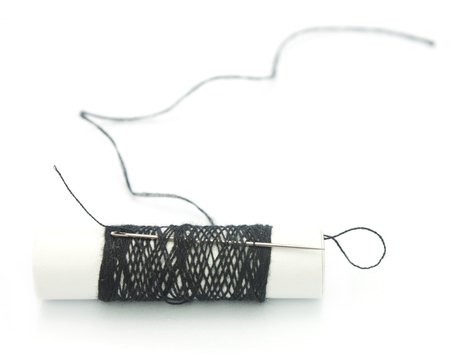 Close-up of needle with black thread in black reelの写真素材