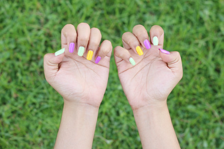 Women hands with nail manicure on green grass backgroundの写真素材