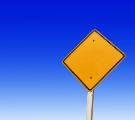 Yellow traffic sign on blue sky background. Copy space for text.の写真素材
