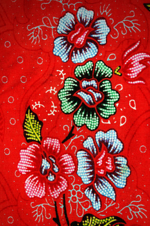 Thai style fabric pattern with flowers on the red cloth background.の写真素材