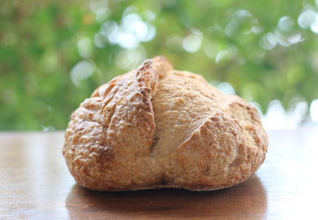 Freshly baked bread on a wooden table with blurred green background.