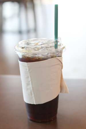 Iced coffee in plastic cup on table in coffee shop, stock photo