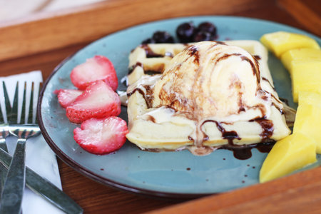 Pancake with strawberry, banana and chocolate sauce on blue plate