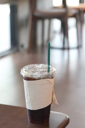 Iced coffee in plastic cup on table in coffee shop, stock photo