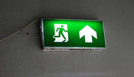 Emergency exit sign on the wall of the building with arrow up.