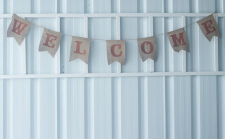 Decorative garland with wooden letters with the word welcome on a white wall