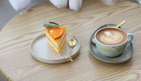 Orange cake and coffee latte art on wooden table in coffee shopの写真素材