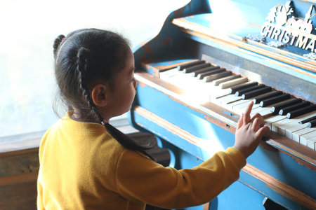 Little girl playing the piano on a sunny day. Selective focus.の写真素材