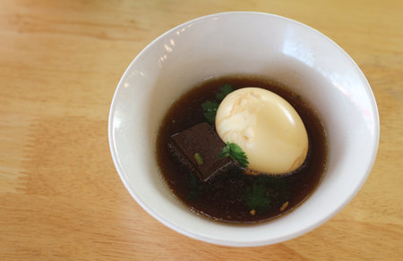 dumpling soup with egg in a bowl on wooden table