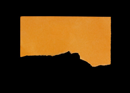 Orange torn paper isolated on black background with copy space for text or image.の写真素材
