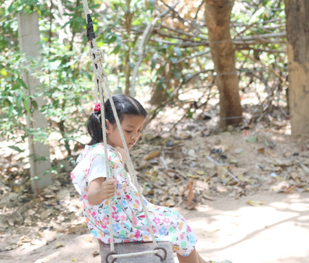 Asian girl swinging on a swing in the garden, Thai children.の写真素材