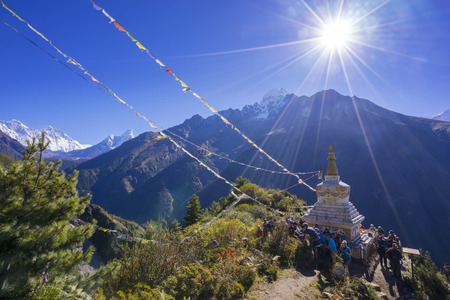 View of a Buddhist stupa and cloud of people with mountain Lhotse and Ama Dablam on the left side behind on the way from Namche Bazaar to Tengboche of the everest base camp trekking route.のeditorial素材