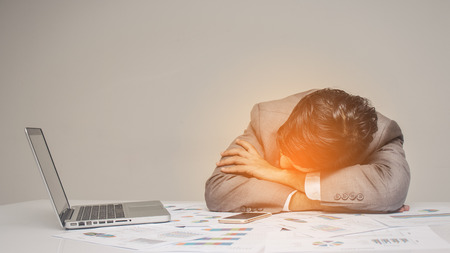 tired businessman asleep on a table while working in officeの写真素材