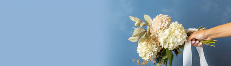 Wide Frame Side Bouquet Of Hydrangeas In Hand With Ribbon Blue Banner Backgroundの素材