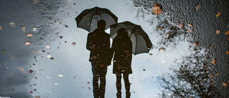 A Couples Reflection In A Puddle With An Umbrella Forming The Words Rainy Day Romance.の素材