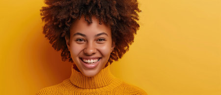 Joyful Woman In Yellow Sweater, Curly Hair, Beaming On Yellow Backdrop.の素材