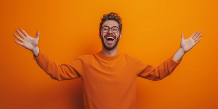 Happy Young Man Enthusiastically Greets Or Farewells Against Vibrant Orange Background. Ð¡oncept Positive Greetings, Colorful Background, Energetic Young Man.の素材
