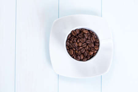 Coffee cup full of coffee beans on a wood tableの写真素材