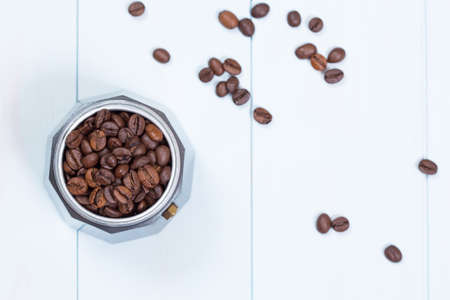 Moka pot full of coffee beans on wooden tableの写真素材