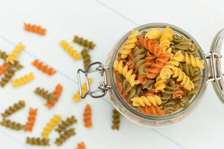 Raw fusilli pasta on a glass jar on blue wood tableの写真素材