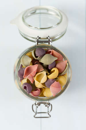 Raw cocciolette pasta on a glass jar on blue wood tableの写真素材