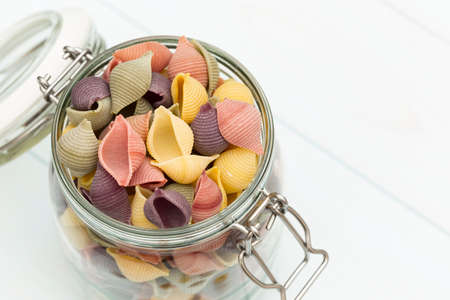 Raw cocciolette pasta on a glass jar on blue wood tableの写真素材