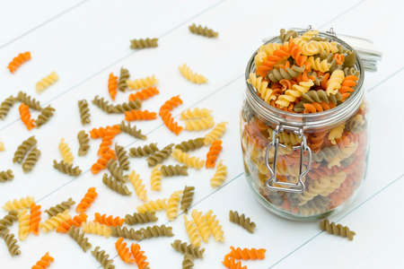 Raw fusilli pasta on a glass jar on blue wood tableの写真素材