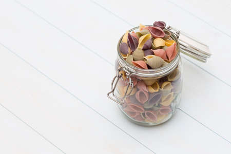 Raw cocciolette pasta on a glass jar on blue wood tableの写真素材