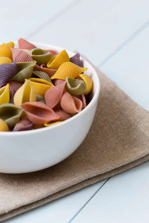 Raw cocciolette pasta in a white bowl on blue wood tableの写真素材