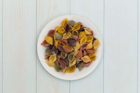 Raw cocciolette pasta in a white plate on blue wood tableの写真素材