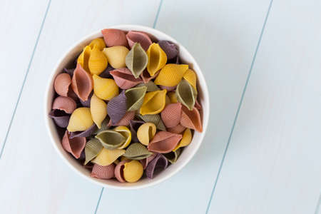 Raw cocciolette pasta in a white bowl on blue wood tableの写真素材