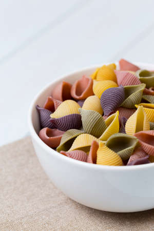 Raw cocciolette pasta in a white bowl on blue wood tableの写真素材