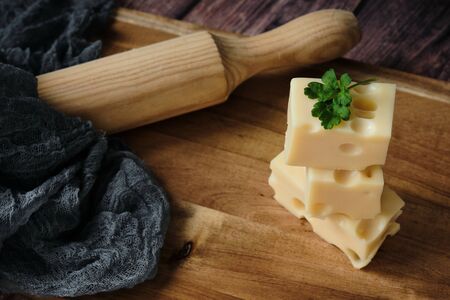 Cheese on dark wooden table background. Close-up pf heap of emmental cheese. Diet and food concept....