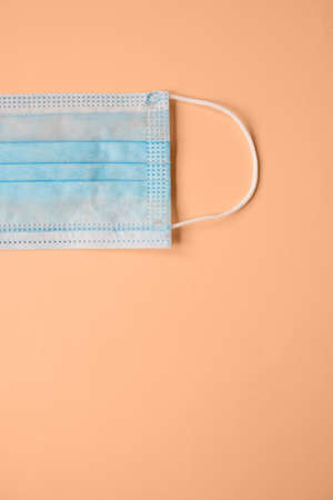 Disposable surgical face mask on orange background. Protection against virus. Healthcare and medical conceptの写真素材