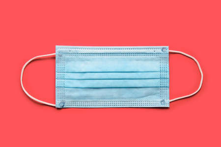 Disposable surgical face mask on red background. Protection against virus. Healthcare and medical conceptの写真素材