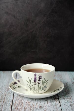 Detail of classic ceramic mug with red tea on a wooden table with dark background and copy spaceの写真素材