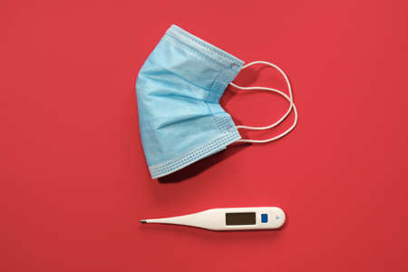 COVID-19 disposable surgical face mask on red background. Protection against coronavirus. Healthcare and medical conceptの写真素材