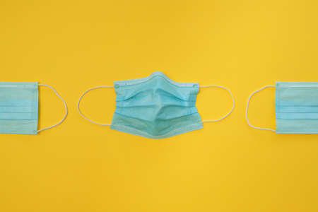 COVID-19 disposable surgical face masks on yellow background. Protection against coronavirus and epidemic. Medical conceptの写真素材