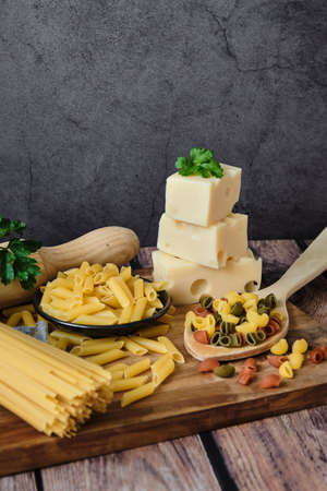 Different raw uncooked Italian pasta on wooden table against dark background. Diet and food concept. Copy space.の写真素材