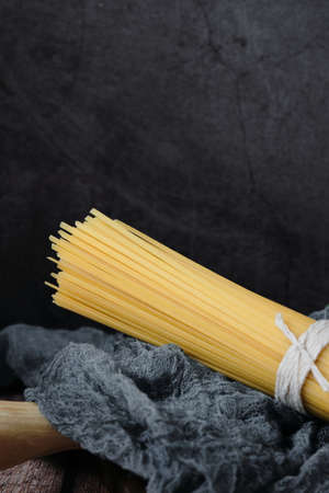 Raw uncooked Italian pasta against dark background. Diet and food concept. Noodles, spaghetti. Copy space. Close up.の写真素材