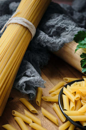 Different raw uncooked Italian pasta on wooden table. Diet and food concept. Close-up.の写真素材