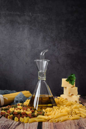 Different raw uncooked Italian pasta and cheese on wooden table. Diet and food concept.の写真素材