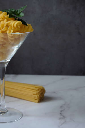 Different raw uncooked Italian pasta and cheese on wooden table. Diet and food concept.の写真素材