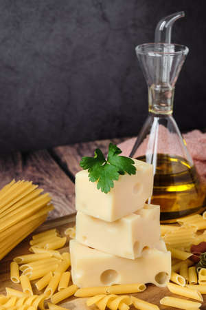 Different raw uncooked Italian pasta and cheese on wooden table. Diet and food concept.の写真素材