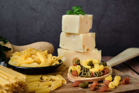 Different raw uncooked Italian pasta and cheese on wooden table. Diet and food concept.の写真素材