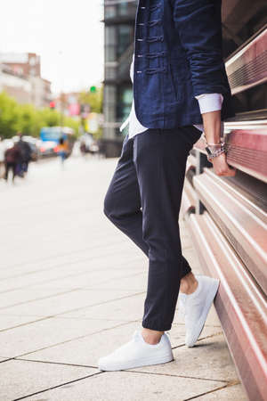 Young man with trendy clothes leaning on a city red wall